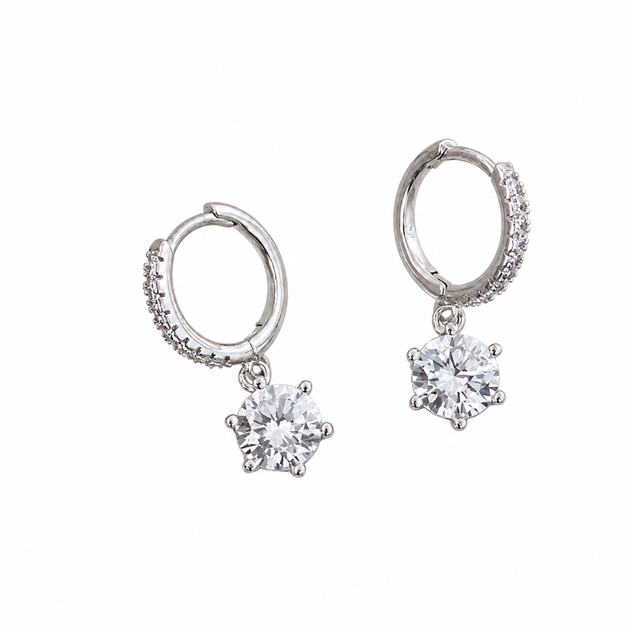 A pair of silver huggie hoop earrings with small pavé accents on the outer edges and a dangling round clear gemstone in a prong setting below each hoop, shown on a plain white background.